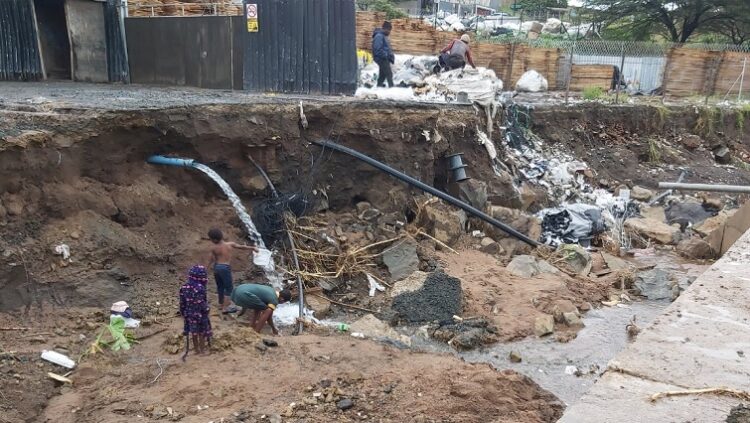 Children collecting water from damaged mains at washed away bridge in KwaDukuza.