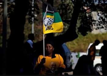 A woman holds up an ANC flag.