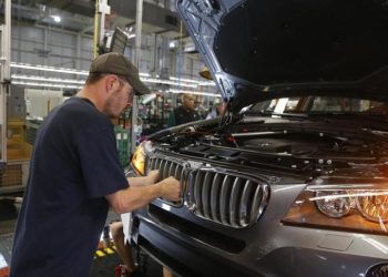 A worker at a BMW plant in the US looking at a new vehicle