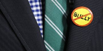 A guest wears an anti-bullying button, which is the logo of the documentary film "Bully" at its Los Angeles premiere in Hollywood March 26, 2012. REUTERS/Danny Moloshok (UNITED STATES - Tags: ENTERTAINMENT) - RTR2ZXNB