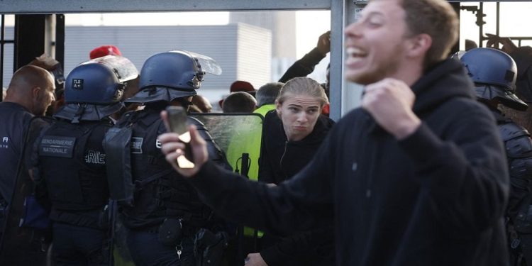 A fan pushes through a police officer inside the stadium as the match is delayed during the Champions League Final at Stade de France on May 28, 2022.