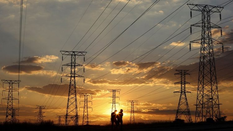Locals walk past electricity pylons during frequent power outages from South African utility Eskom, caused by its aging coal-fired plants, in Soweto, South Africa April 4, 2022.