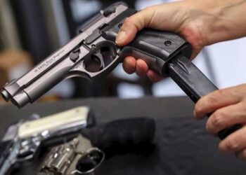 A customer looks over a 9mm hand gun at the Guns-R-Us gun shop in Phoenix.