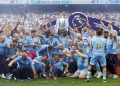 Manchester City's Fernandinho lifts the trophy with teammates and the coaches after winning the Premier League.