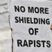 A person holds up a sign against the shielding of rapists