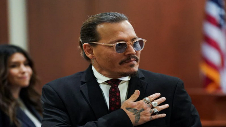 Actor Johnny Depp puts his hand to his heart, acknowledging supporters, during a break in his defamation trial against his ex-wife Amber Heard at the Fairfax County Circuit Courthouse in Fairfax, Virginia, U.S., May 18, 2022.