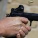 A man shoots a pistol at a shooting range.