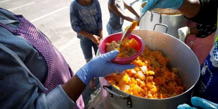 Volunteers dish up a meal for children.