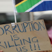 [File image]: A person holds a placard written: "Corruption is killing us!!!"