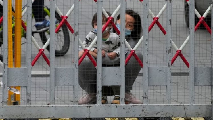 A resident and a child look out through gaps in the barriers at a closed residential area during lockdown, amid the coronavirus disease (COVID-19) pandemic, in Shanghai, China, May 10, 2022.