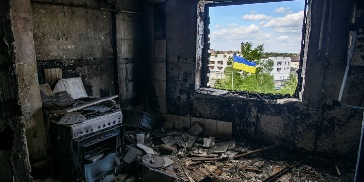 Ukrainian national flag is seen through the window of an apartment destroyed during Russia's invasion of Ukraine in the town of Borodianka, in Kyiv region, Ukraine May 13, 2022.