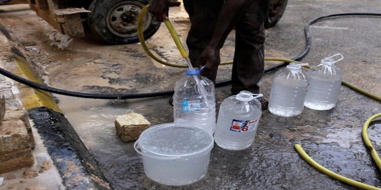 A man is pictured refilling bottles from a water tanker.