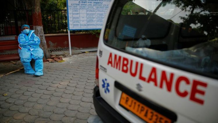 A health worker rests as he sits next to his ambulance carrying a dead body of a victim who died due to the coronavirus disease (COVID-19), at a crematorium in New Delhi, India, May 10, 2021.