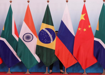 A staff worker stands behind the national flags of Brazil, Russia, China, South Africa and India to tidy the flags before a group photo during the BRICS Summit at the Xiamen International Conference and Exhibition Center in Xiamen, southeastern China's Fujian Province, China September 4, 2017.
