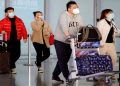People wearing protective face masks carry their luggage at Capital Airport, following an outbreak of the coronavirus disease (COVID-19), in Beijing, China, November 5, 2020.