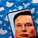 An image of Elon Musk is seen on smartphone placed on printed Twitter logos in this picture illustration.