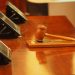 Gavel and block pictured on a table inside of a court room.