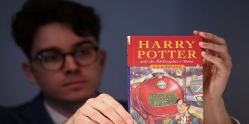 A person holds a rare first edition and signed by the author copy of 'Harry Potter and the Philosophers Stone' by British author J.K. Rowling, which is to be put up for auction at Christie's auction house in London, Britain May 31, 2022.