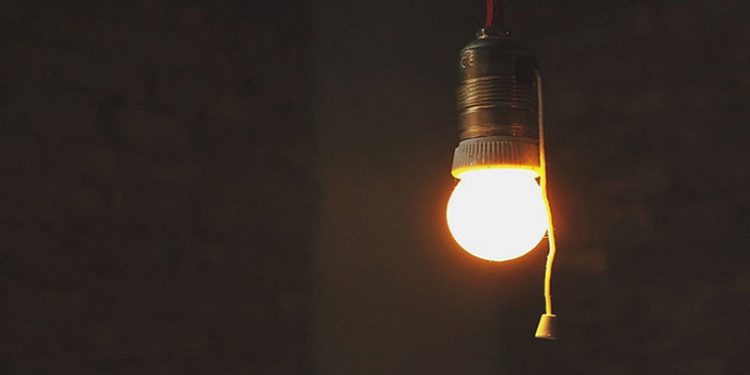 A light bulb shines in a dark room.
