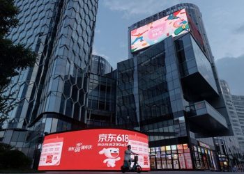 A person rides a scooter past a JD.com advertisement for the "618" shopping festival in a shopping district in Beijing, China June 14, 2022. REUTERS