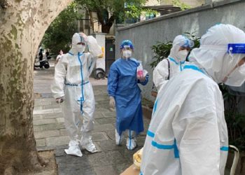Workers in protective suits walk on a street, following the coronavirus disease (COVID-19) outbreak, in Shanghai, China June 9, 2022.