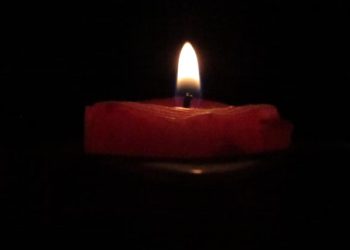 A candle lit in a dark room.