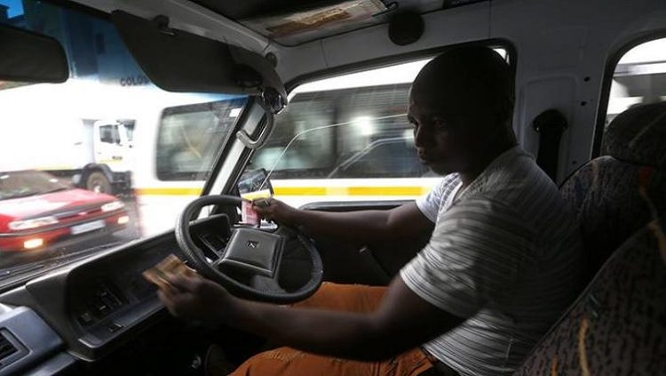 Minibus taxi driver Zakes Hadebe counts fares after making his first run of the day ferrying passengers from Soweto township to central Johannesburg February 21, 2014.