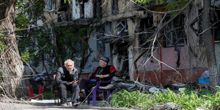 [File Image] Local residents sit in a courtyard near a block of flats heavily damaged during the Ukraine-Russia conflict, in the southern port city of Mariupol, Ukraine May 20, 2022.