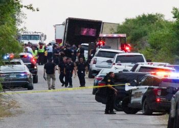 Law enforcement officers work at the scene where people were found dead inside a trailer truck.