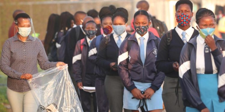 A teacher distributes masks to students as schools begin to reopen after the coronavirus disease (COVID-19) lockdown in Langa township in Cape Town, South Africa June 8, 2020
