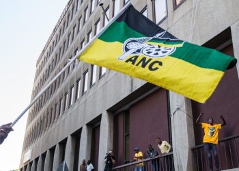 Supporter holding an ANC flag with other supporters in the background