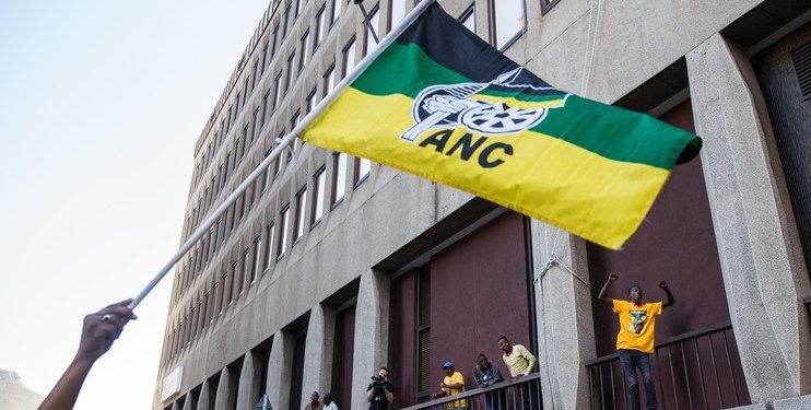 Supporter holding an ANC flag with other supporters in the background