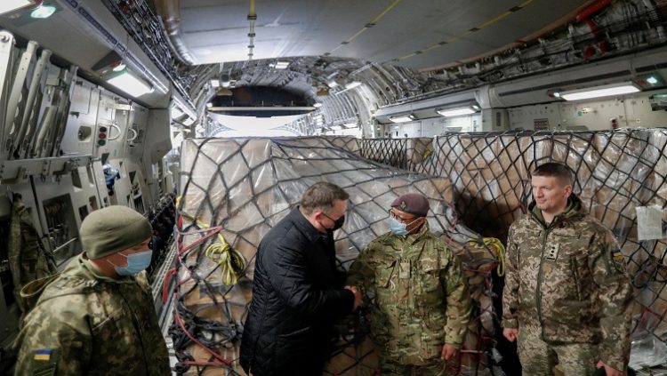 Officials, including British and Ukrainian service members, greet each other before the unloading of a shipment of Britain's security support package for Ukraine, delivered by a C17 Globemaster III aircraft of the Royal Air Force, at the Boryspil International Airport outside Kyiv, Ukraine, February 9, 2022.