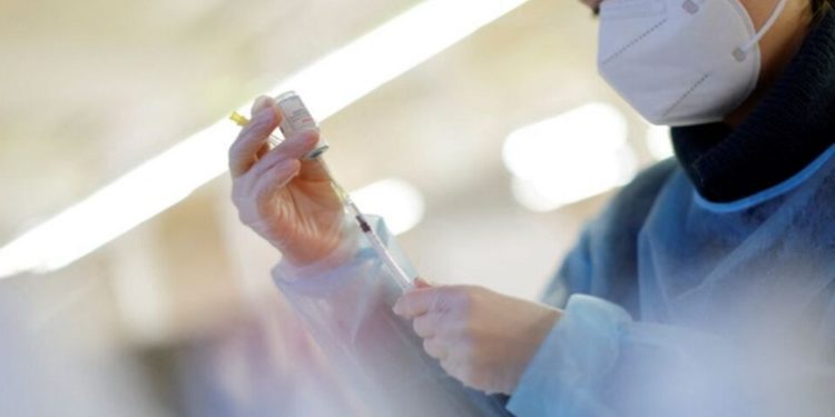A nurse prepares a booster dose of a COVID-19 vaccine