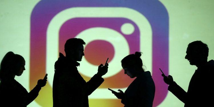 FILE PHOTO: Silhouettes of mobile users are seen next to a screen projection of Instagram logo in this picture illustration taken March 28, 2018.