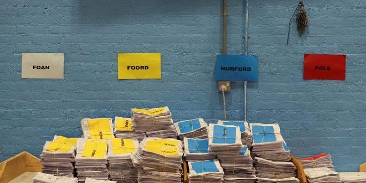 Colour-coded stacks of votes are pictured under posters with names of candidates for the Tiverton and Honiton by-election, at Lords Meadow Leisure Centre in Devon, Britain, June 24, 2022.