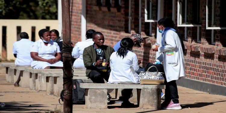 Zimbabwean medical workers sit outside Sally Mugabe Hospital during a strike by state doctors and nurses to press for higher pay, in Harare, Zimbabwe. REUTERS/Philimon Bulawayo