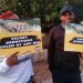 Two ANC staff members hold up boards as they picket outside NASREC conference centre