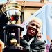A smiling Banyana Banyana player with the WAFCON trophy at the Union Buildings