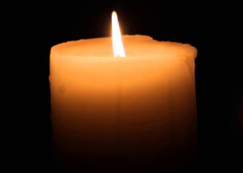 A candle burns at a memorial.