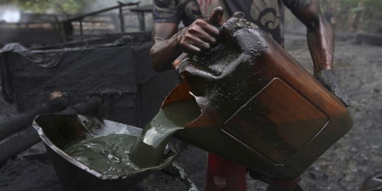 A worker pours crude oil into a locally made burner using a funnel at an illegal oil refinery site near river Nun in Nigeria's oil state of Bayelsa.