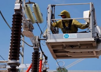 [FILE IMAGE] A technician wearing a protective suit works on a live 250 000 high voltage power line of a RTE (Electricity Transport Network) electrical substation in Grande-Synthe, France, July 1, 2021.
