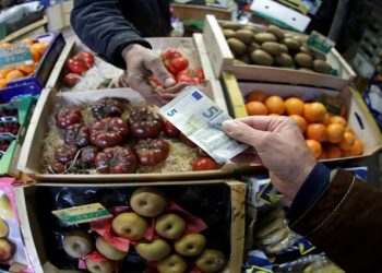 A shopper pays with a euro bank note in a market in Nice, France,