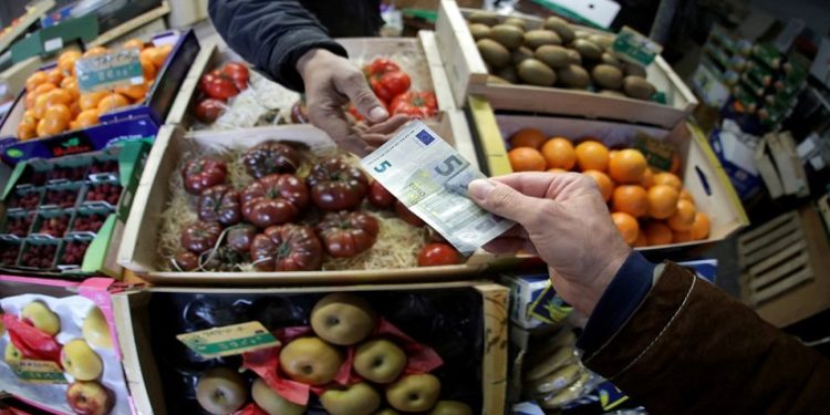A shopper pays with a euro bank note in a market in Nice, France,