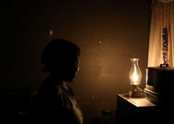 A woman looks on next to a parafin light during an electricity load-shedding in Soweto, South Africa, March 2021.