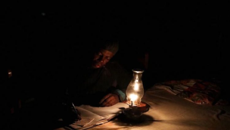 Mpumelelo Mapota works next to a paraffin lamp during a power outage, June 9, 2021.