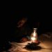 Mpumelelo Mapota works next to a paraffin lamp during a power outage, June 9, 2021.