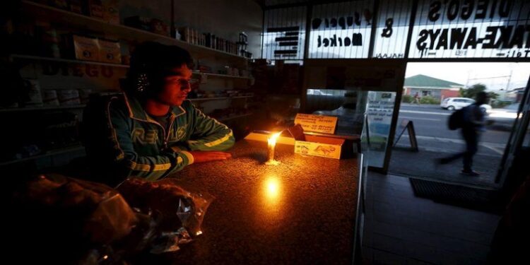 Small business owner sits with a candle during a power outage