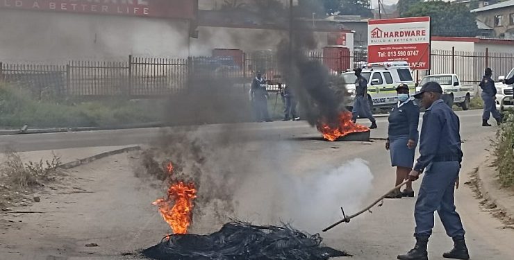 A police officer seen next to burning tyres during protests in Mbombela, Mpumalanga, 07 July 2022