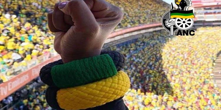 A person holds up a fist with ANC colours on an armband